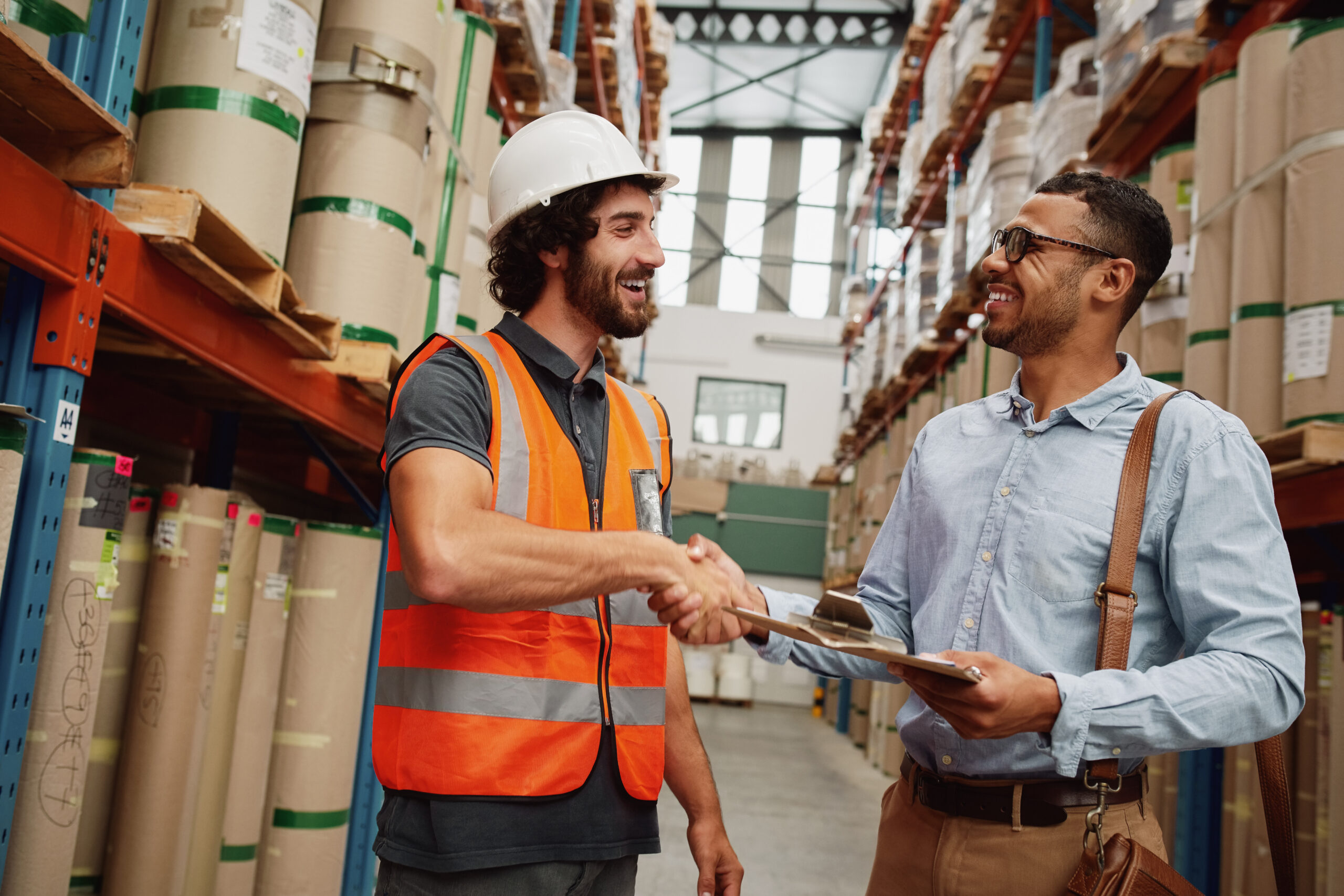 Warehouse worker shaking hands with a customer in a distribution facility.