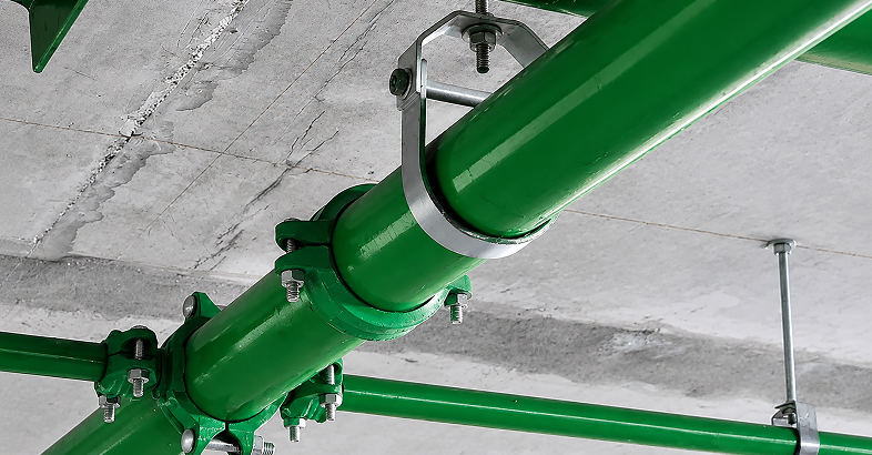 Green commercial piping secured to a concrete ceiling with Piers pipe supports.