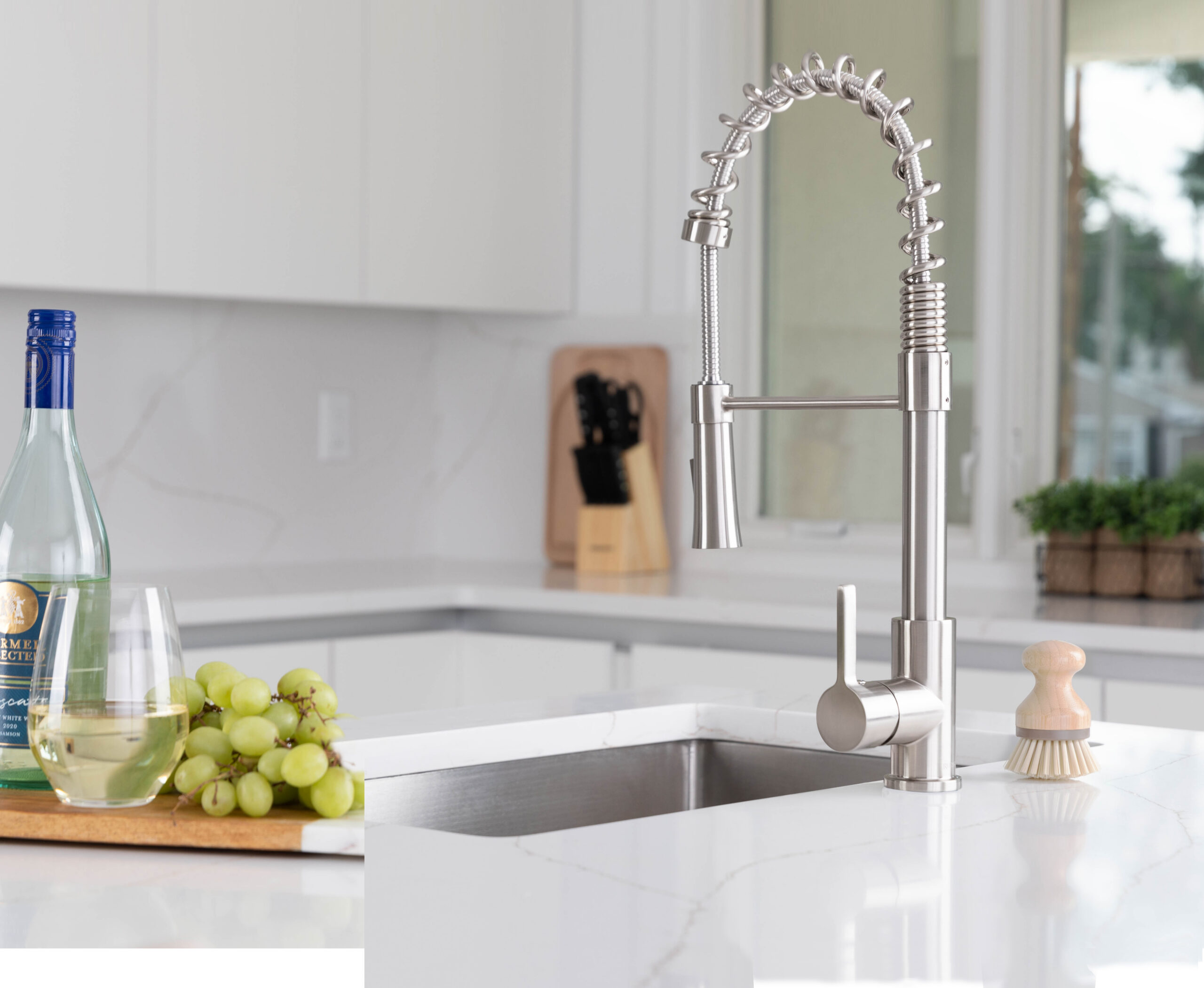 Modern stainless steel pull-down kitchen faucet installed over a kitchen sink.