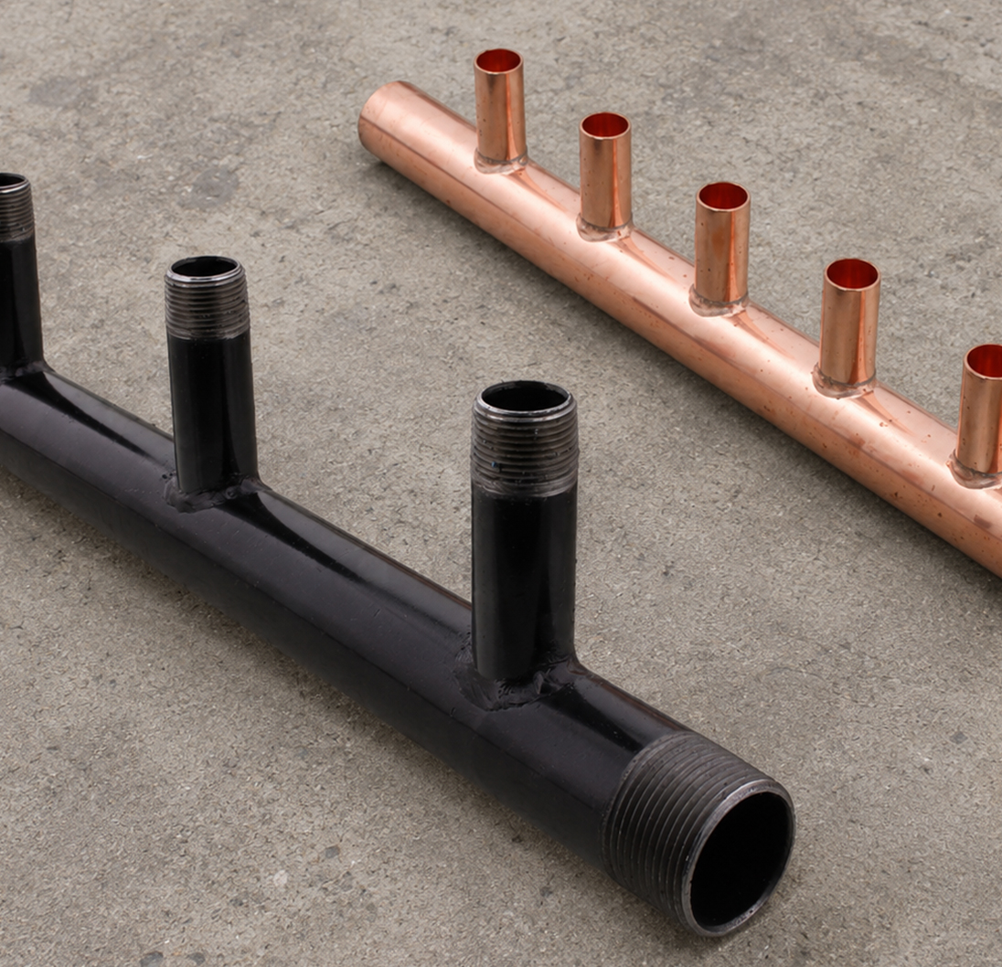 Copper and black steel plumbing manifolds with multiple branch connections.
