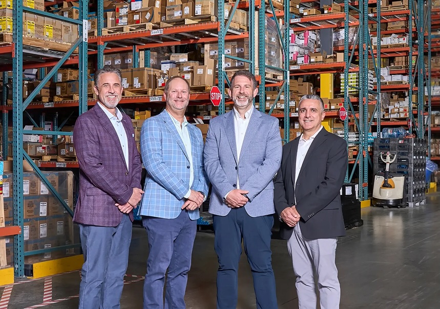 Sharply dressed Everflow leadership team at a warehouse supporting wholesale plumbing distribution.