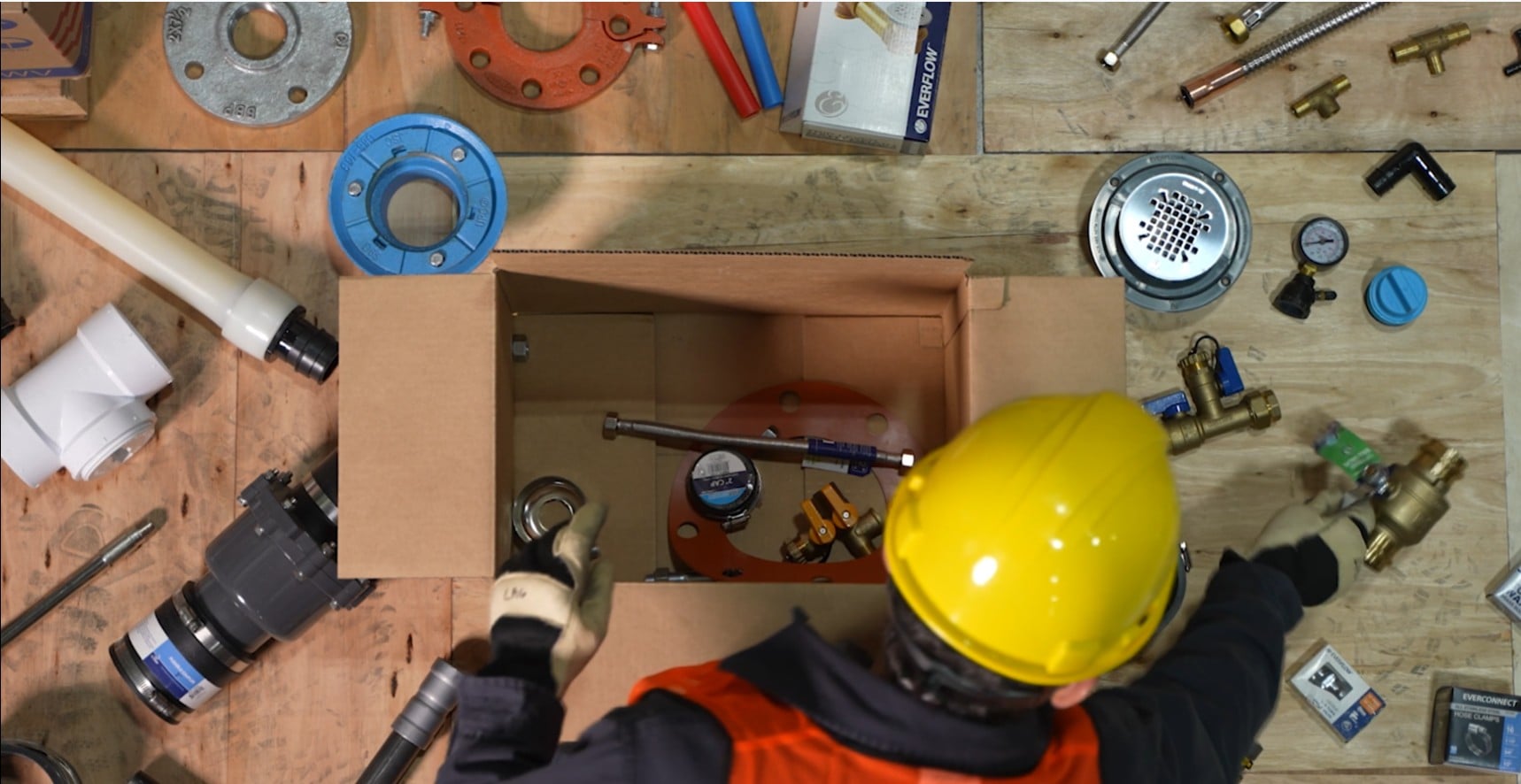 Worker packing plumbing fittings and supplies for warehouse order fulfillment.