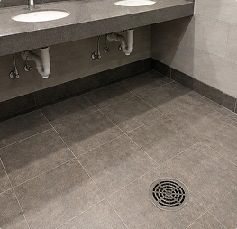 Commercial floor drain installed in a tiled restroom for reliable drainage and water management.